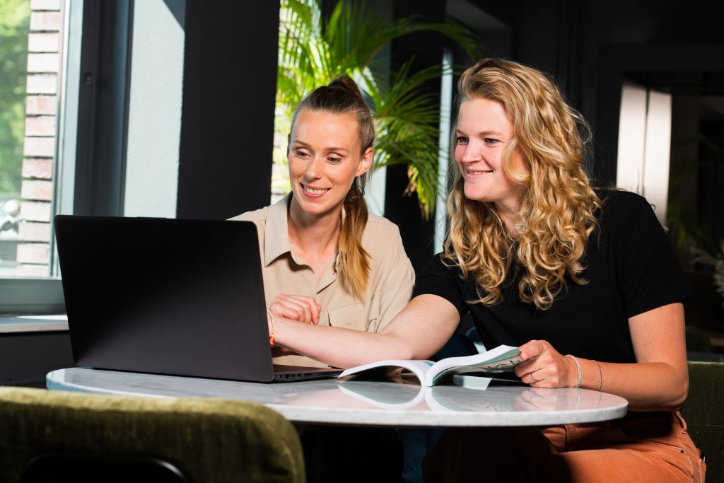 Trainee Anna en Docente Violet kijken naar een scherm op de laptop tijdens een Blended Learning sessie